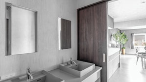 A modern bathroom with two sinks, a large mirror, and a wooden door leading to a dining area. - THE ARKLUNE (Sapporo)