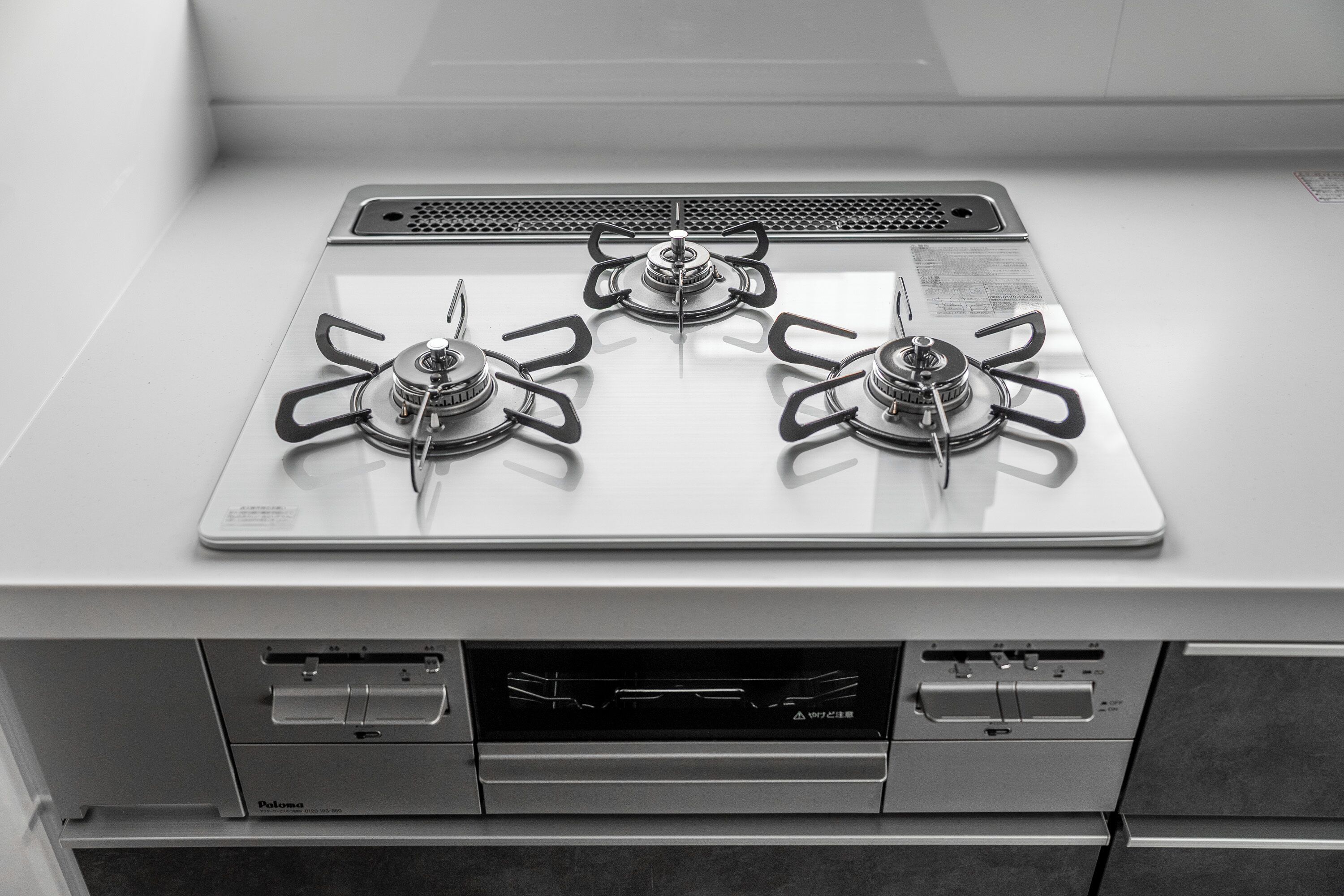 A kitchen with three gas burners and a built-in oven.