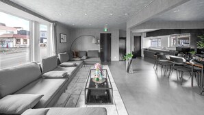 A modern hotel lobby with a sofa, a coffee table, a bar area, and a view of the street. - THE ARKLUNE (Sapporo)