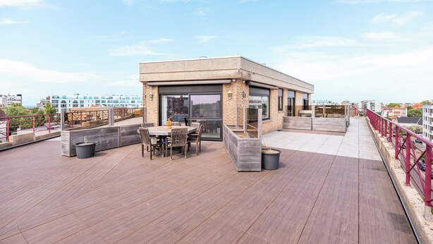 A rooftop terrace with a dining area, a small building, and a view of the cityscape. - Beautiful penthouse flat with central location (Koksijde)