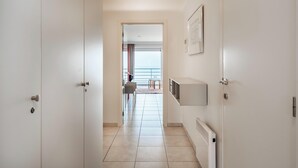 A hallway with a view to a balcony and a door with a radiator. - Cosy flat with frontal sea view (Koksijde)