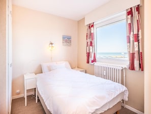 A bedroom with a bed, bedside table, lamp, and a window with curtains.