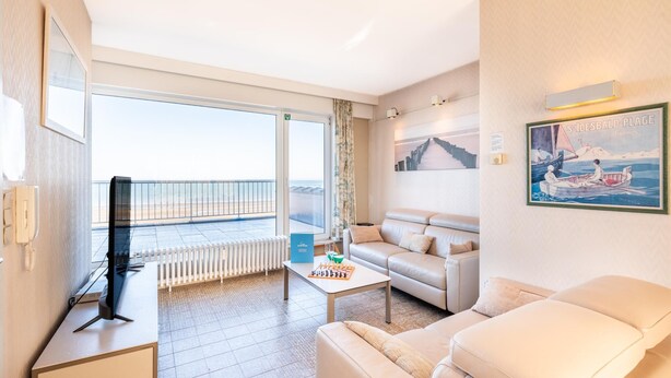Habitació d'hotel amb un balcó, un sofà, una taula de cafè i un quadre.