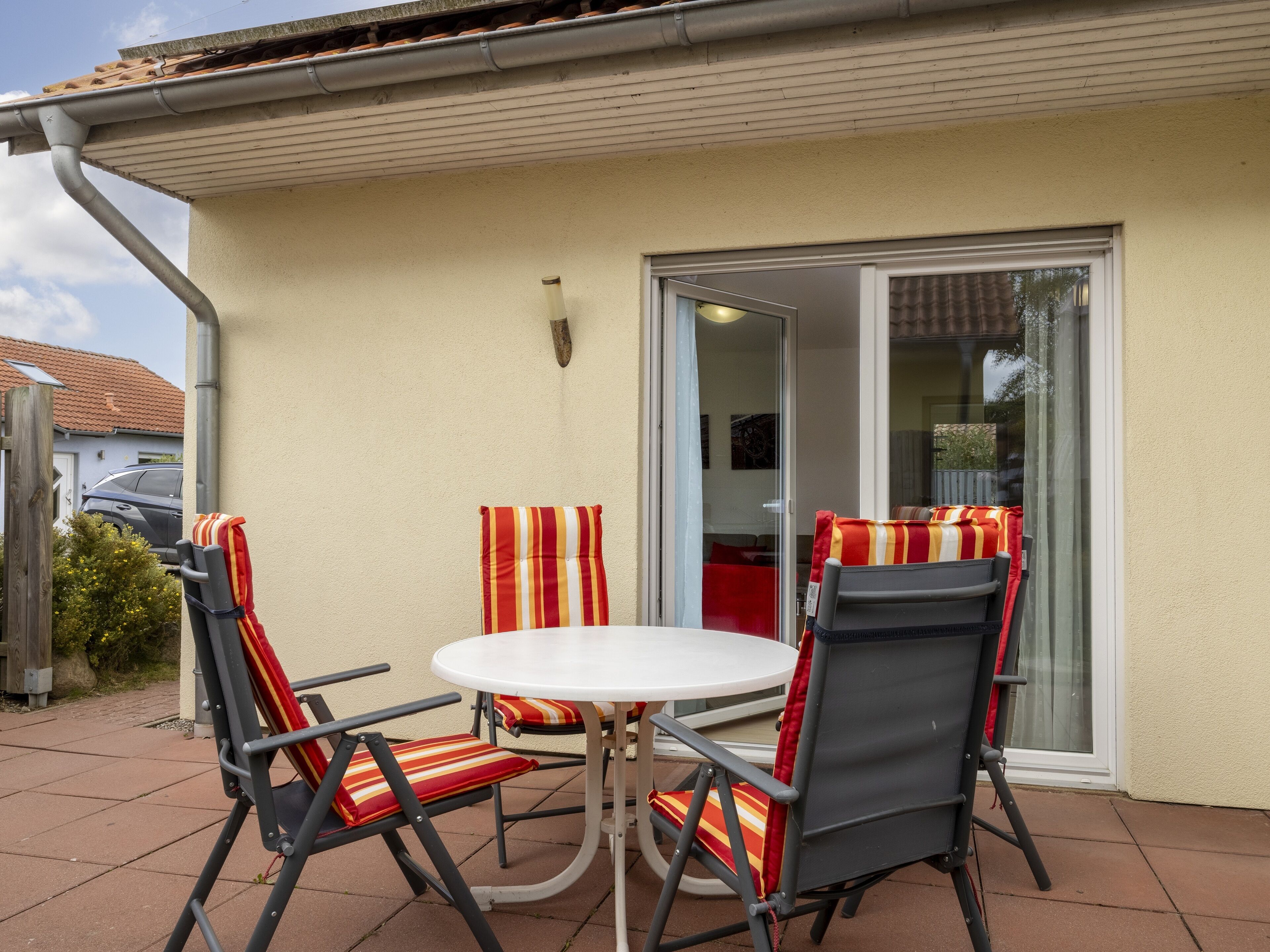 An outdoor patio with a round table and four chairs, each with striped cushions.