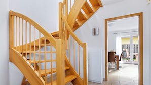 A wooden staircase leading to an upper floor, a white door, and a view of an outdoor patio area with a table and chairs. - Cosy holiday home ideal for 2 families (Boiensdorf)