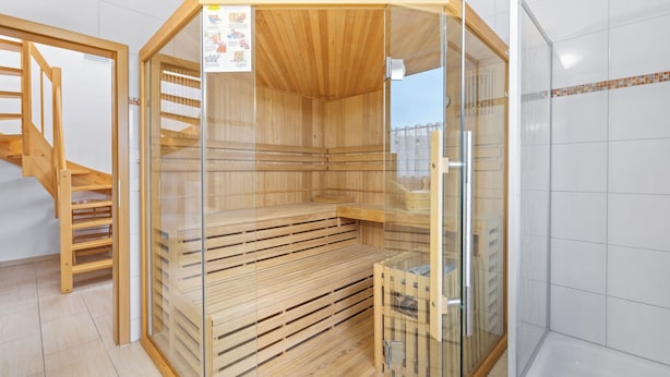A sauna with wooden benches and a glass enclosure. - Cosy holiday home ideal for 2 families (Boiensdorf)