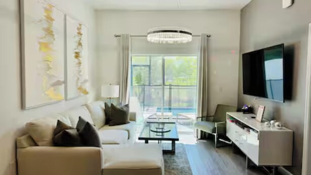 A modern living room with a sofa, coffee table, and TV. - The Sun-Kissed Retreat / near Disney (Davenport)