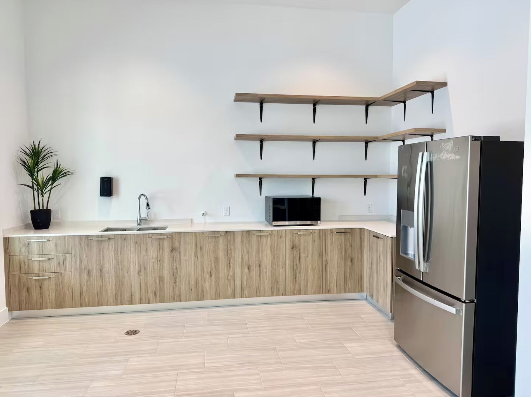 Une cuisine moderne dotée d’un îlot central intégré, d’appareils électroménagers en acier inoxydable et de meubles de rangement en bois.
