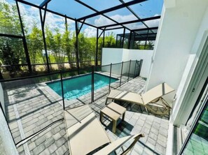 A modern outdoor pool area with a glass enclosure, a pool, and lounge chairs.