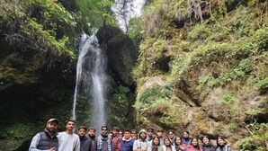 Un grup de persones al costat d'una cascada en un entorn natural.