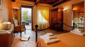 Un dormitorio con cama, una silla, una lámpara, una ventana con cortinas y vistas al exterior.