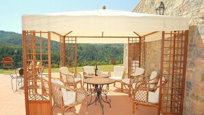 Un patio al aire libre con mobiliario de mimbre, una mesa redonda y un toldo.