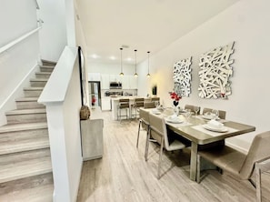 Une cuisine moderne avec des armoires blanches, des appareils en acier inoxydable et des luminaires suspendus.