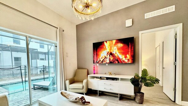 Ein modernes Wohnzimmer mit großem Fernseher, einem weißen Sofa, einem Couchtisch und einer Pflanze.