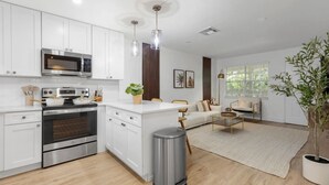 A modern kitchen with white cabinets, stainless steel appliances, and a central island.