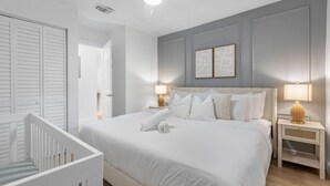 A bedroom with a large bed, two bedside tables, a ceiling fan, and a door.