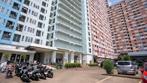 A multi-story building with a parking area in front. - Tamastu Blue Sapphire Apartel Cakung (Jakarta)