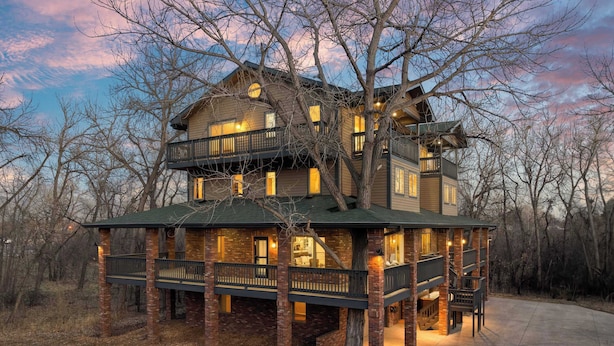 A multi-story log cabin with a balcony, surrounded by trees. - Ultimate Treehouse Mansion w/ Swim Spa, Sleeps 31 (Lakewood)