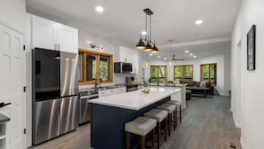 A modern kitchen with stainless steel appliances, a large island, and pendant lighting. - Ultimate Treehouse Mansion w/ Swim Spa, Sleeps 31 (Lakewood)