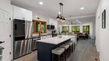 A modern kitchen with stainless steel appliances, a large island, and pendant lighting.