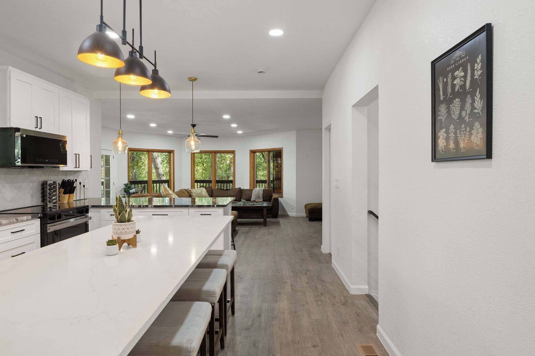 A spacious kitchen with a large island, pendant lighting, and a dining area with a view of trees.