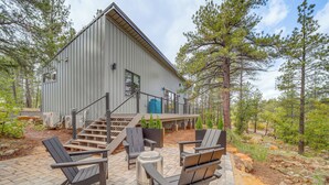 A modern building with a metal exterior, a staircase leading to a deck, and outdoor seating with Adirondack chairs. - Modern Cabin Living! Mtn-View Gem in Munds Park (Munds Park)