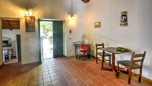 A dining area with a table and chairs, a desk with a chair, and a door leading outside. - Villa Pascal C: A characteristic and welcoming apartment that is part of a villa surrounded by meadows and by green hills, with Free WI-FI. (Mirto)