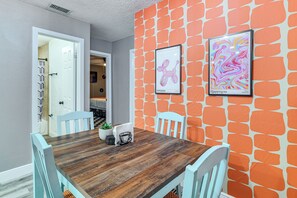 A dining area with a wooden table, white chairs, and orange patterned walls. - 9 Mi to Legoland: Family Gem w/ Games Galore! (Winter Haven)