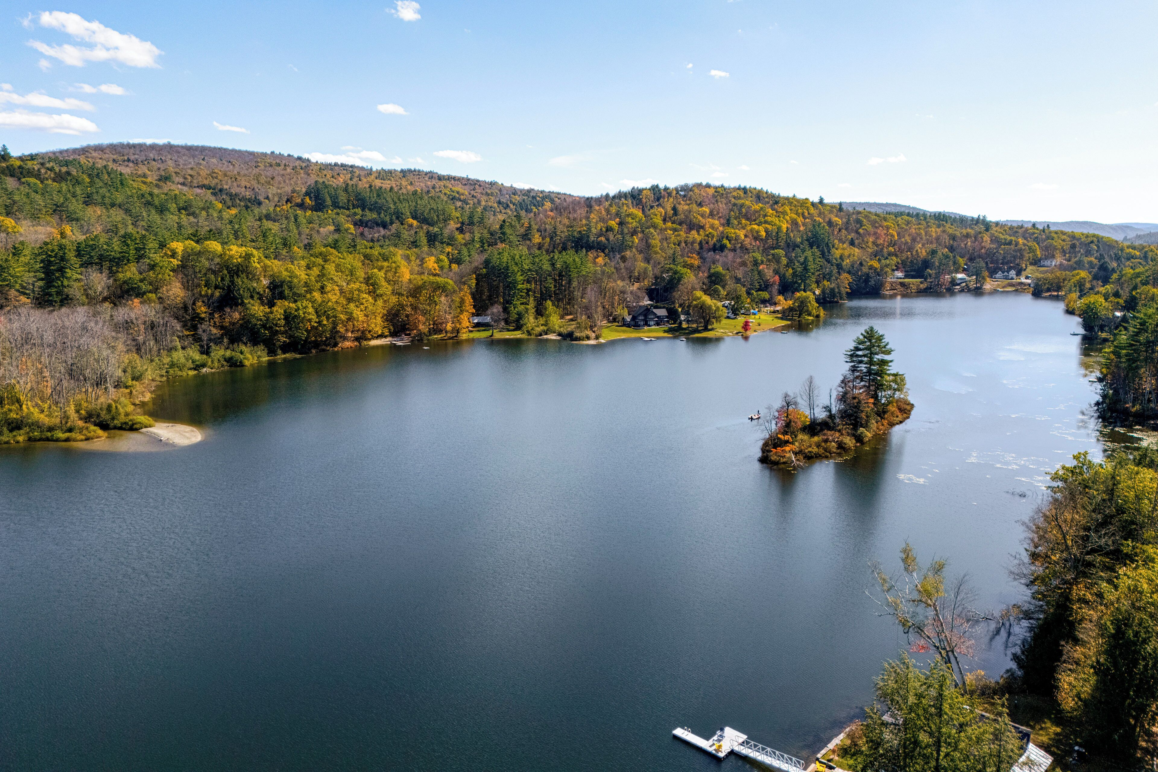 A lake surrounded by forested hills with a dock extending into the water.