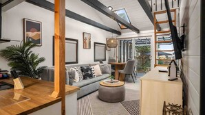 A modern living room with a grey sofa, wooden coffee table, and a dining area with a wooden table and chairs.