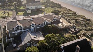 A coastal property with multiple houses, a beach, and a small dock.