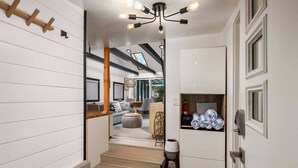 A modern interior with a staircase leading to a living area, a ceiling light fixture, and a door with towels.