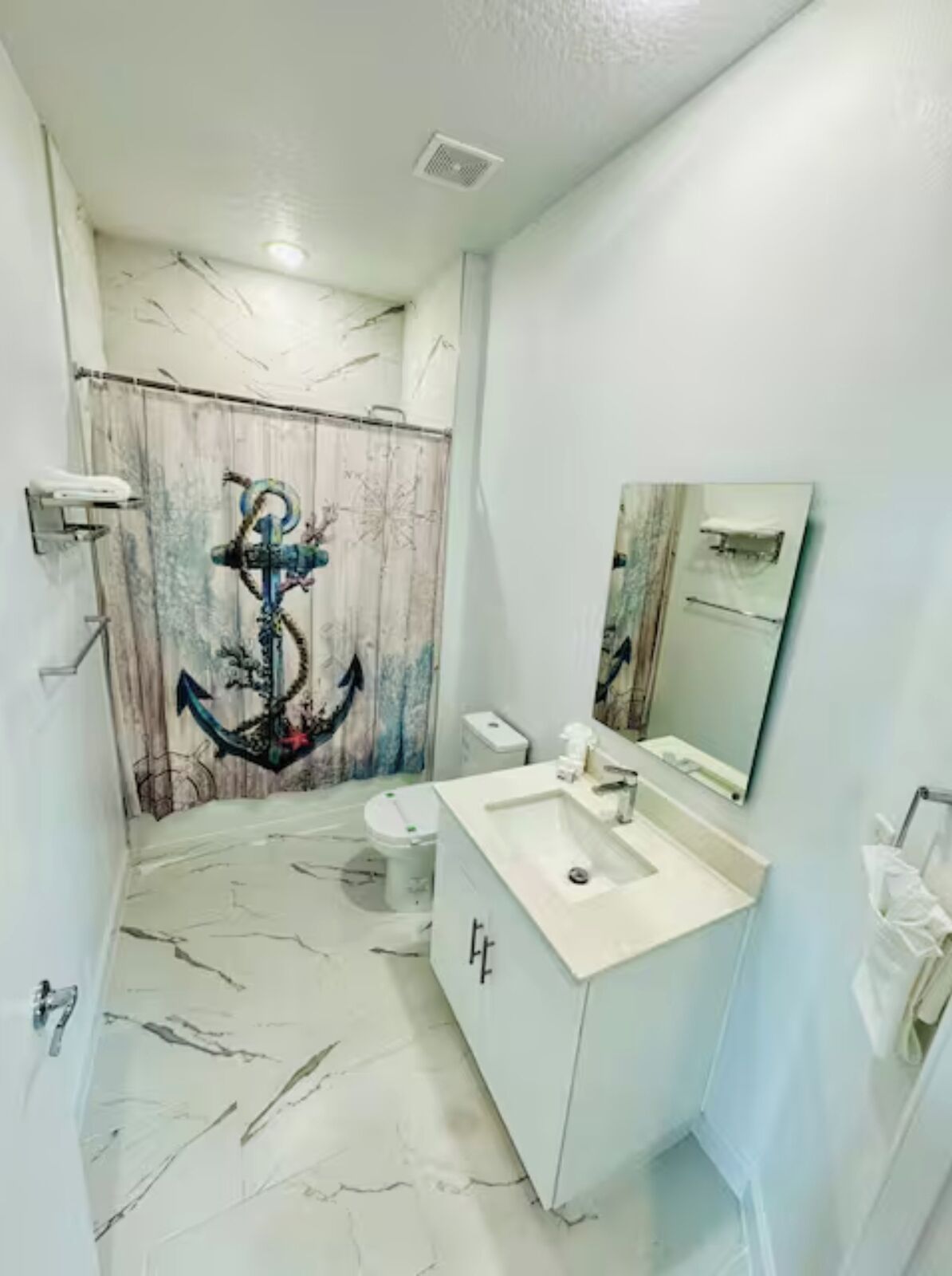 Un bany amb sòl de marbre, un lavabo amb mirall i un vàter.