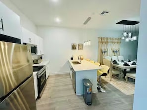 Una cocina moderna con electrodomésticos de acero inoxidable, una isla central y un comedor con mesa y sillas.
