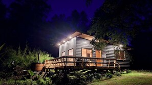 Eine Holzhütte mit einer Terrasse, umgeben von viel Grün.