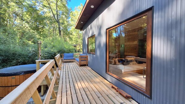 A wooden deck with outdoor seating and a hot tub.