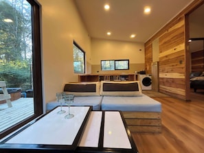 Een moderne kamer met een bank, een tafel met glazen, een wasmachine en houten wanden.