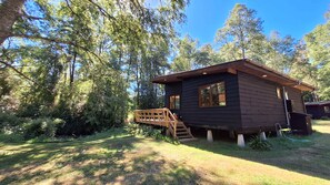 A cabin with a wooden deck, surrounded by dense forest. - Cypress Cabin - Riverside Hot Tub & Wood Stove (Huiscapi)