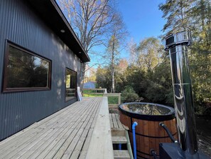Ein modernes Gebäude mit großen Fenstern, einer Holzterrasse und einem Whirlpool.