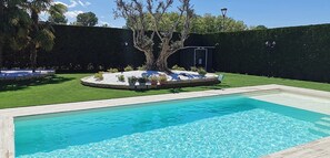 Une piscine rectangulaire avec une terrasse en bois au premier plan.