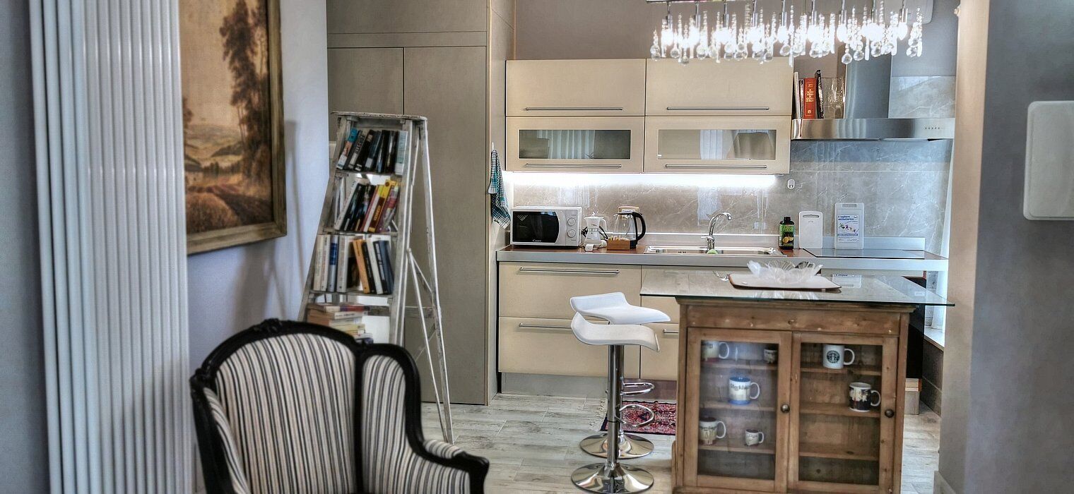 Una cocina moderna con barra, una estantería y una araña.