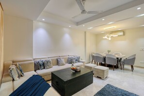 Una sala de estar moderna con sofá, mesa de centro y comedor con sillas.