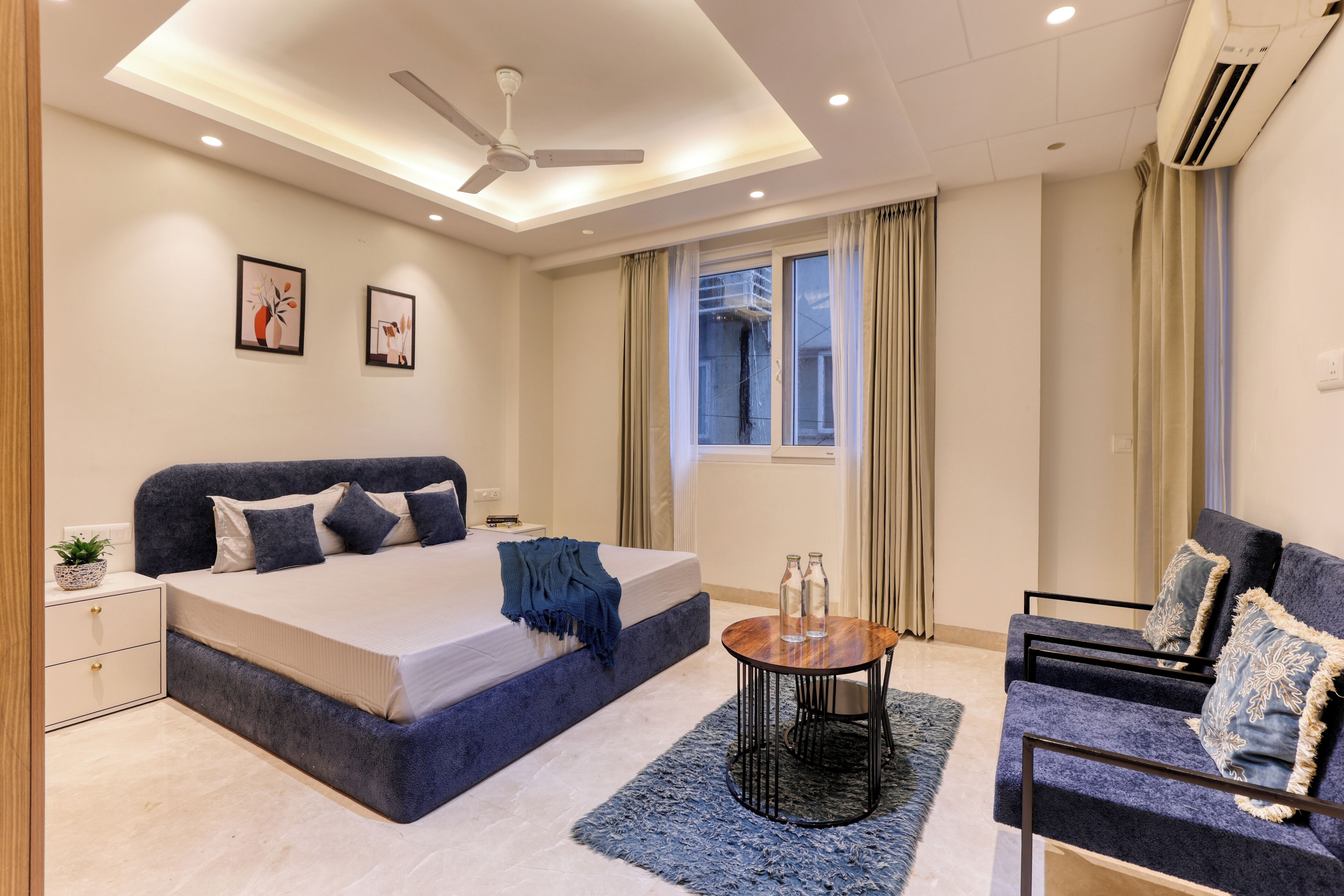 Ein modernes Schlafzimmer mit einem großen Bett, einer Couch, einem kleinen Tisch und einem Deckenventilator.