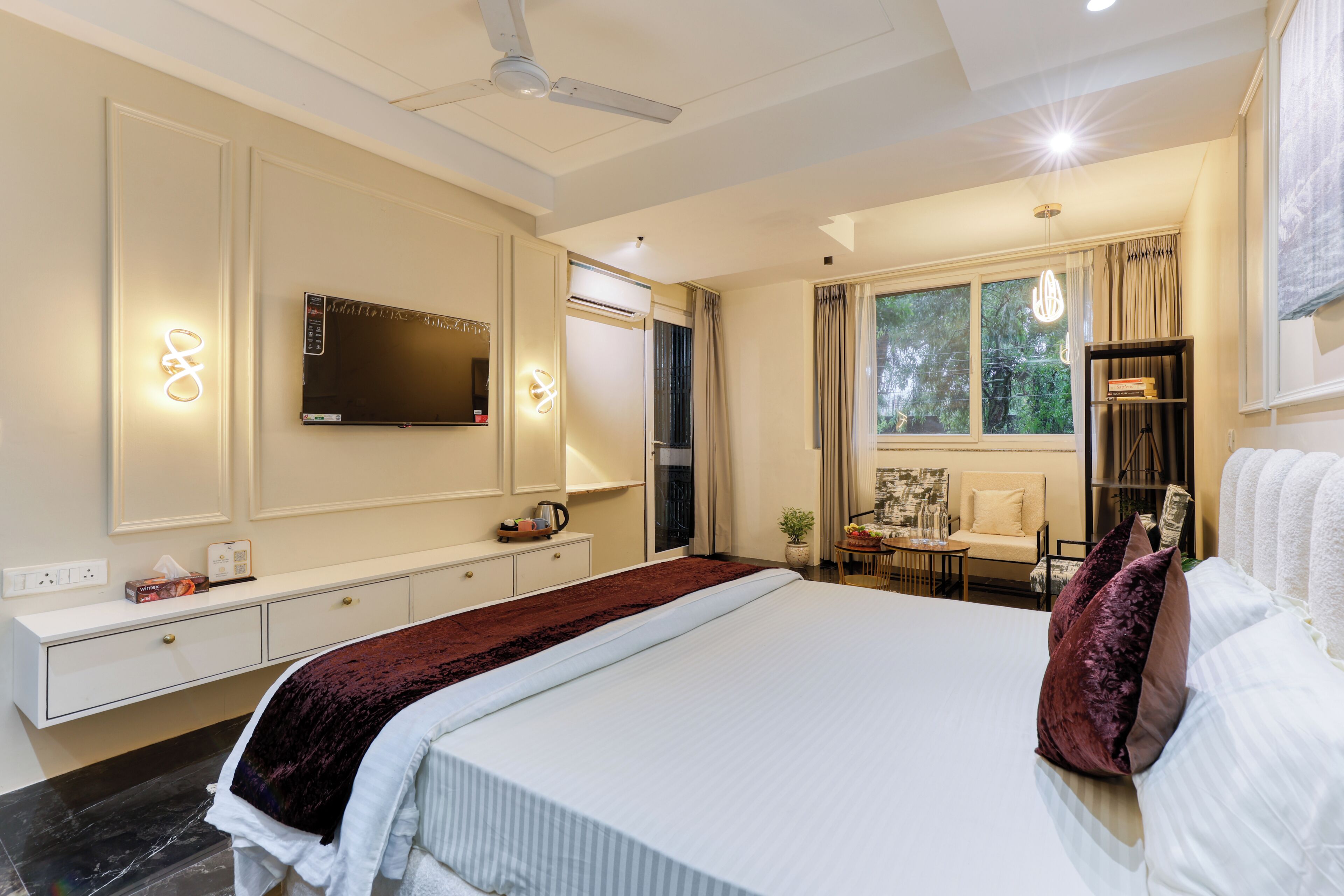 Una habitación de hotel moderna con una cama grande, televisión de pantalla plana, escritorio con silla y ventana con cortinas.