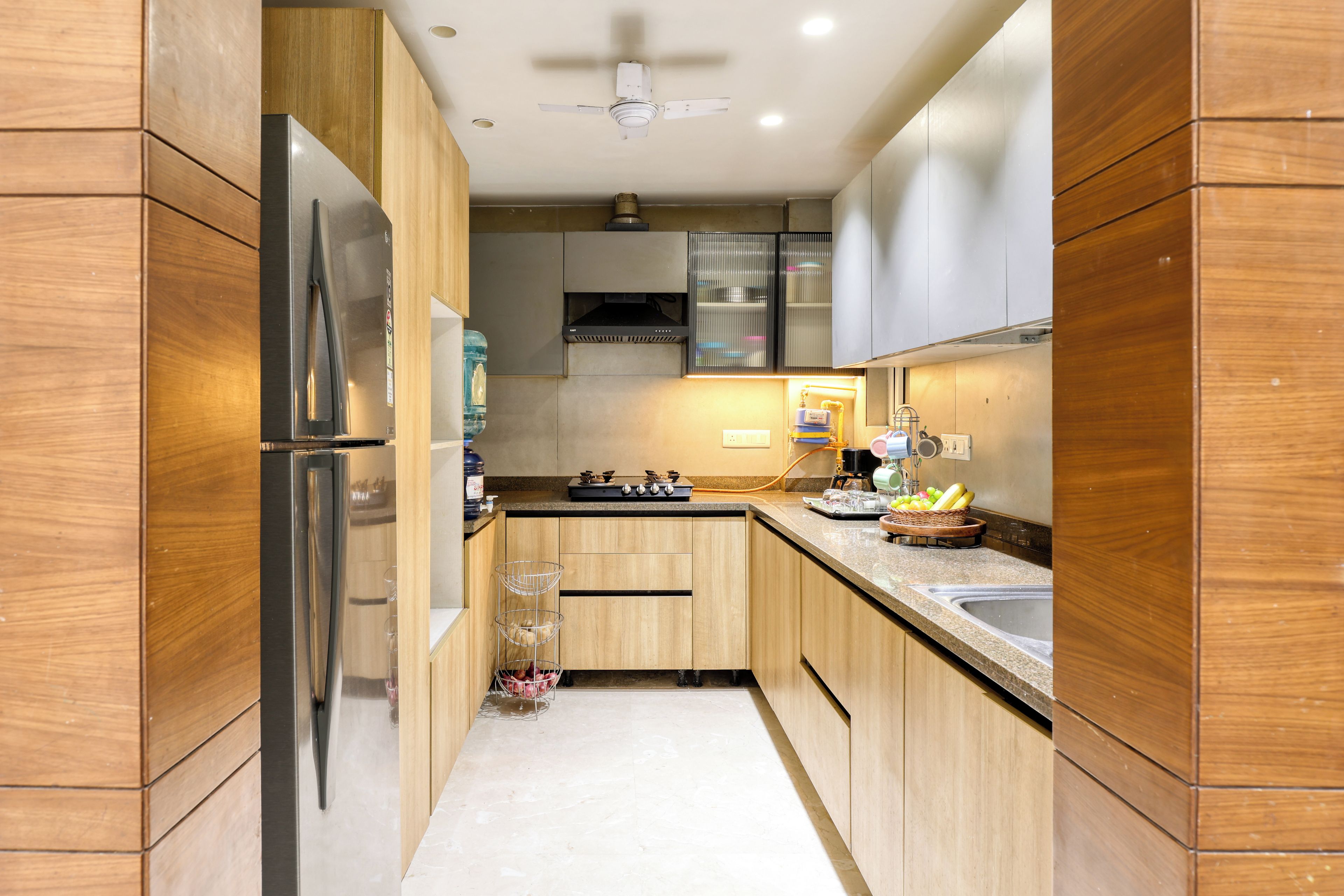 A modern kitchen with wooden cabinets, a stainless steel refrigerator, and a built-in oven.