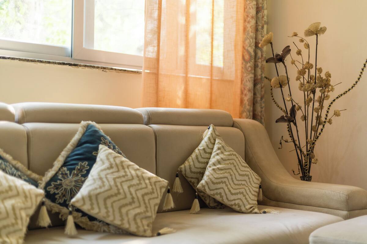 A sofa with patterned cushions and a vase with dried flowers.