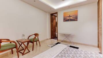 A room with a ceiling fan, a painting of an airplane, a wooden chair, a small table, and a folded blanket.