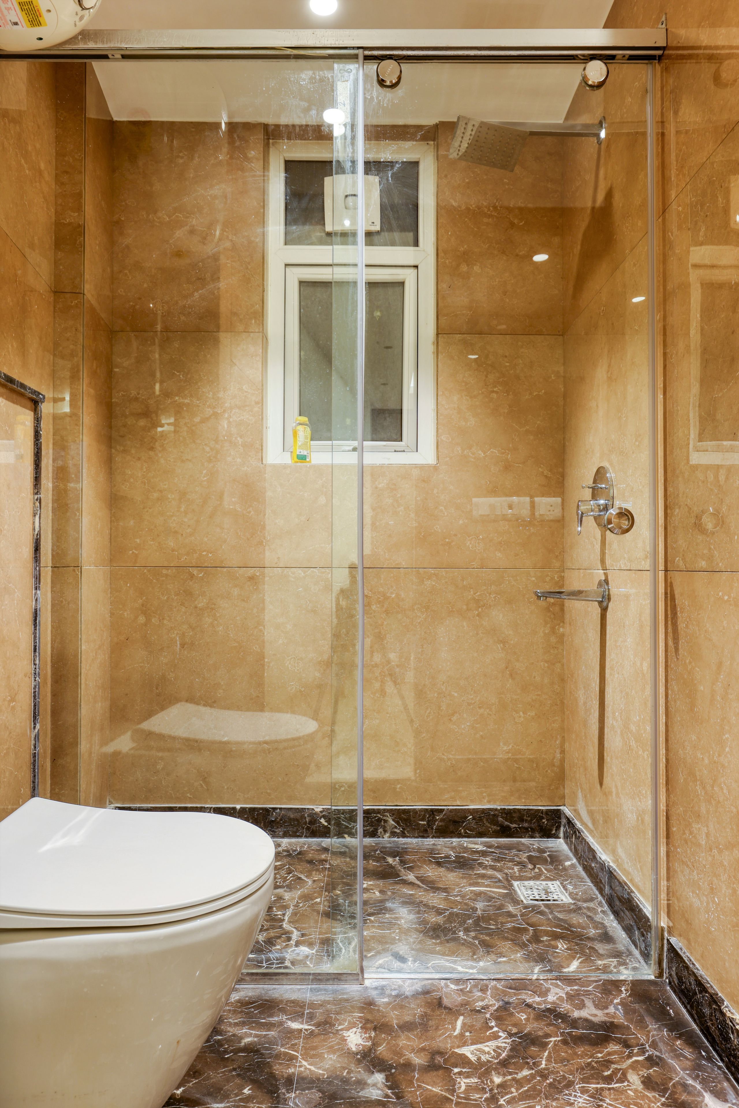 Une salle de bain avec une douche à parois de verre, des toilettes et un sol en marbre.