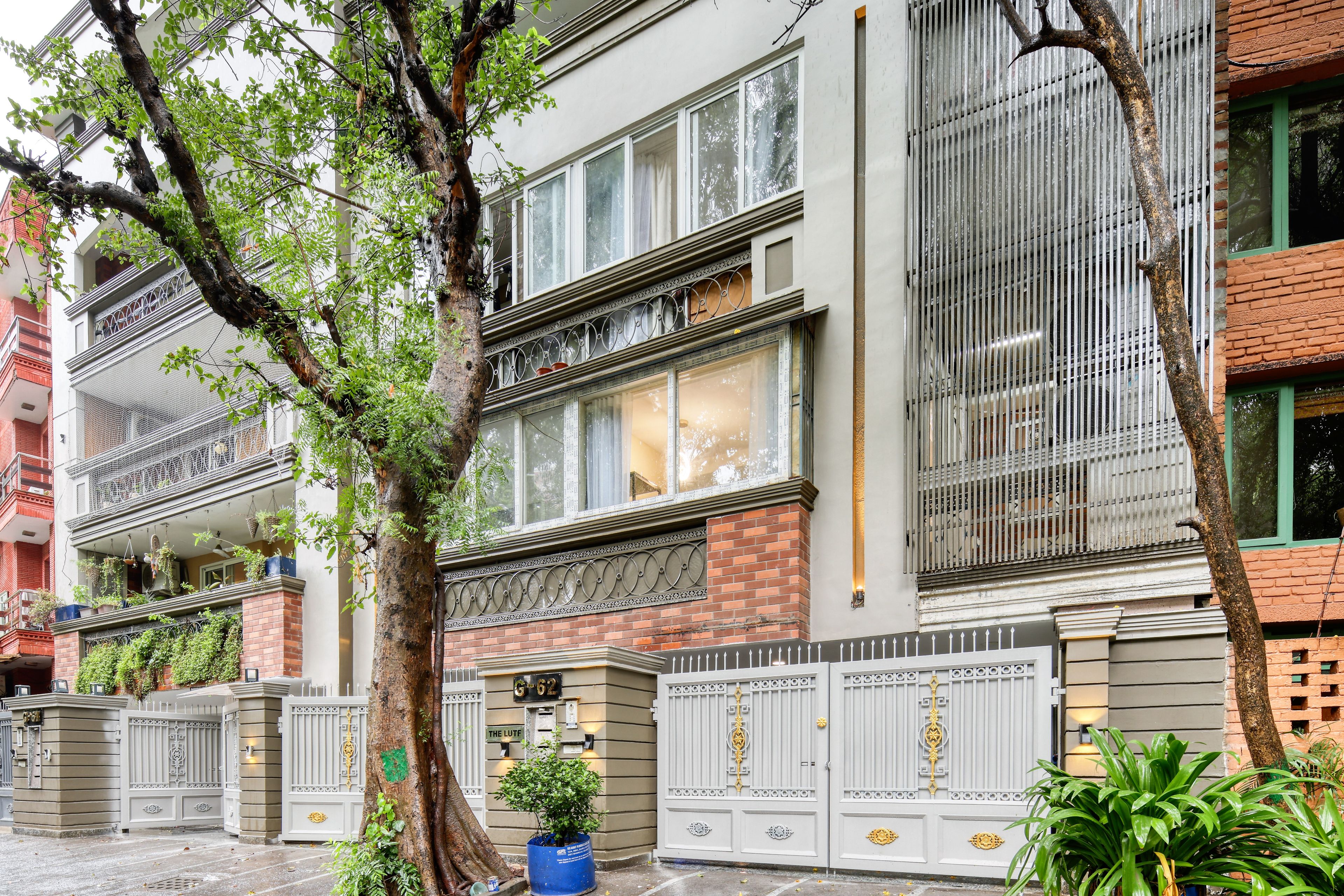 A multi-story building with a gated entrance, large windows, and a balcony with plants.