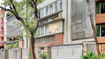 A multi-story building with a gated entrance, large windows, and a balcony with plants.
